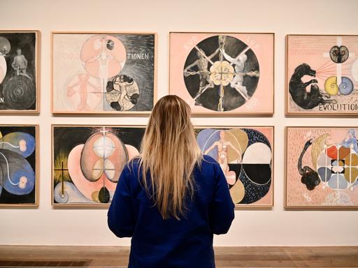 Eine Betrachterin steht vor Gemälden von Hilma af Klint in London.