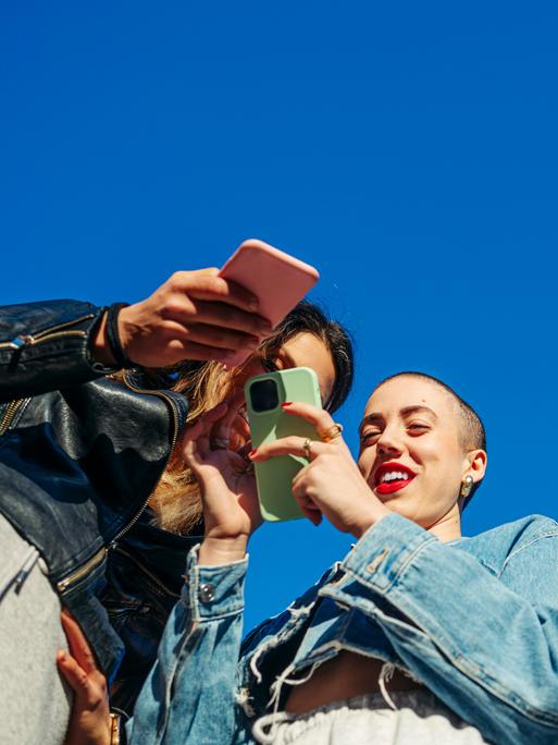 Untersicht auf eine Gruppe von jungen Menschen mit Smartphones.