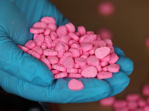 Eine Person hält Ecstasy-Tabletten in der Hand. 