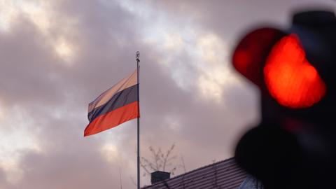 Die Flagge der Russischen Botschaft weht am frühen Morgen vor einer roten Ampel. Die russische Armee ist am frühen Morgen in die Ukraine einmarschiert.