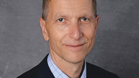 Porträt von Michael Höhme, dem Schulleiter des Lessing-Gymnasiums Döbeln vor blauem Hintergrund.
