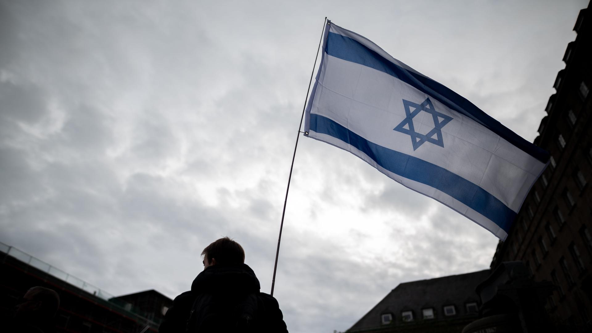 Ein Mann hält auf einer Solidaritätskundgebung für Israel eine Israel-Flagge in der Hand.