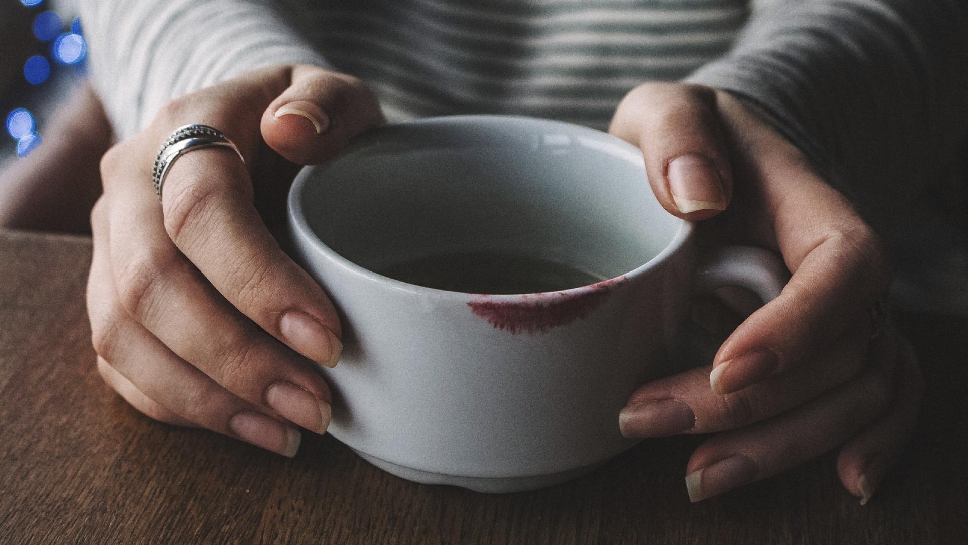 MIDSECTION OF WOMAN WITH COFFEE CUP