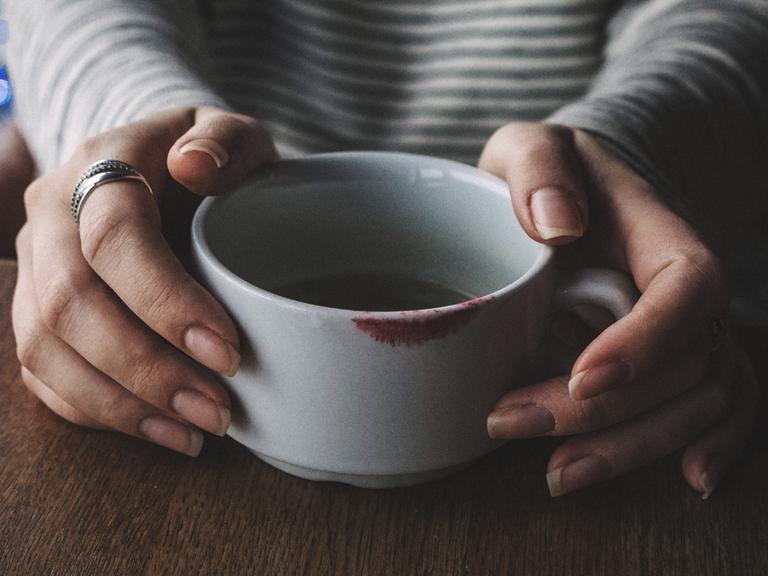 MIDSECTION OF WOMAN WITH COFFEE CUP