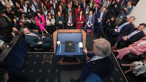 Von der Bühne aus betrachtet sieht man die Menge der Reporter während einer Pressekonferenz. Im Vordergrund steht Präsident Trump an einem Rednerpult.