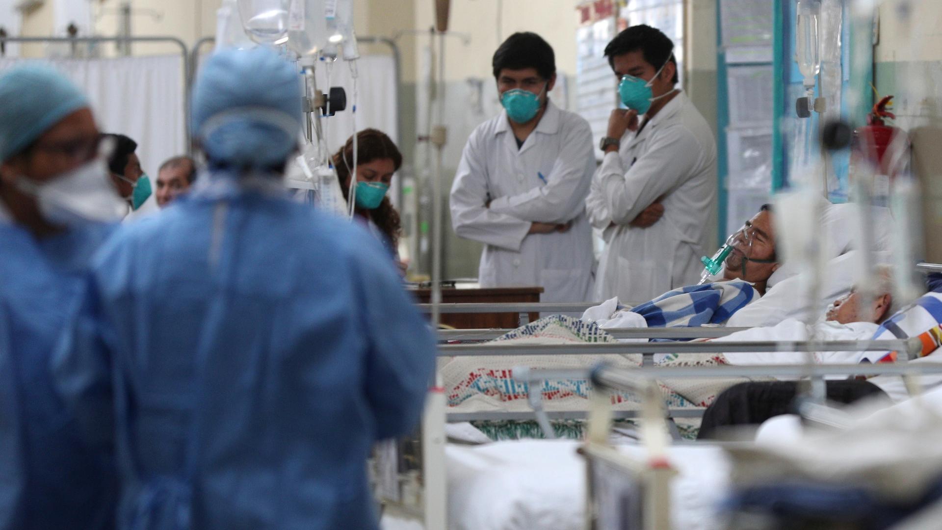 Krankenhaus in Lima, Peru mit Pflegern und medizinischem Personal in blauen und weißen Uniformen sowie Kranken in Betten.