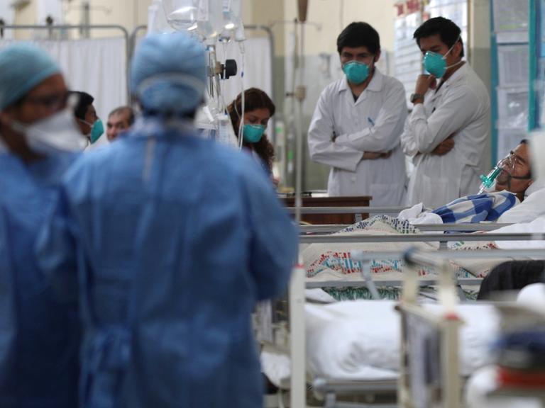 Krankenhaus in Lima, Peru mit Pflegern und medizinischem Personal in blauen und weißen Uniformen sowie Kranken in Betten.
