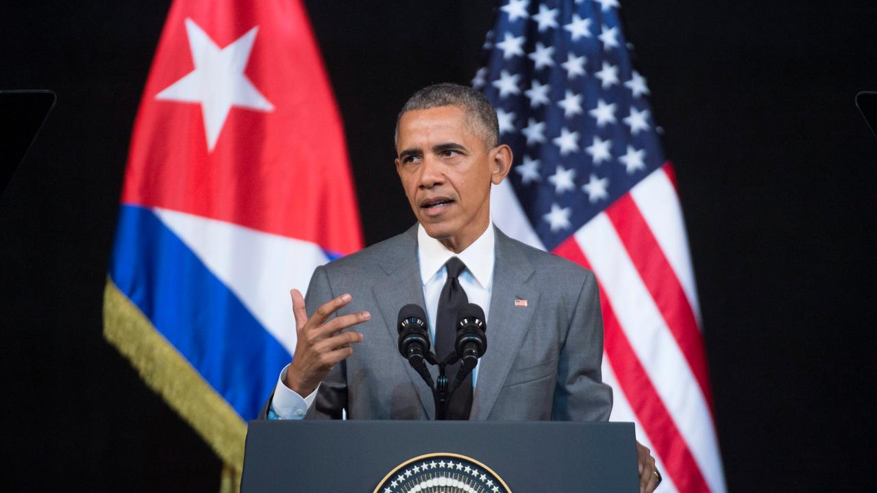 US-Präsident Barack Obama steht an einem Rednerpult, hinter ihm sieht man verschwommen Flaggen von Kuba und den USA US-Präsident Barack Obama steht an einem Rednerpult, hinter ihm sieht man verschwommen Flaggen von Kuba und den USA