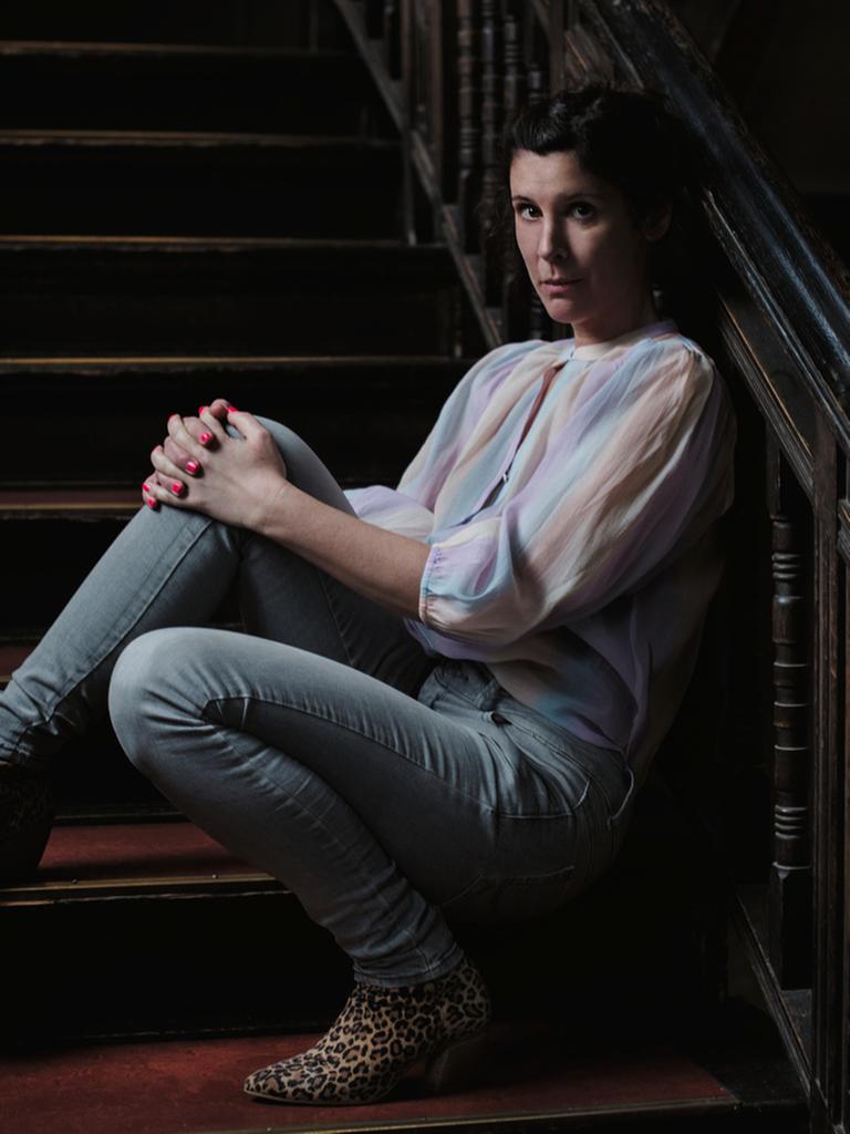Die Autorin Daniela Droescher sitzt auf der Treppe eines Hausaufgangs und lehnt an das Geländer.
