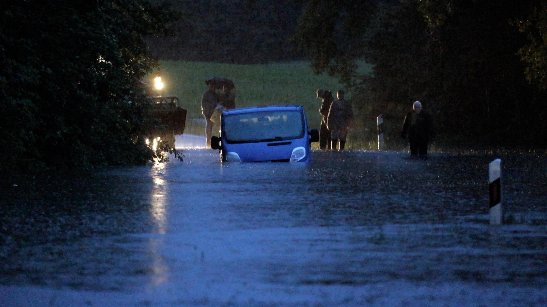 Ein Fahrzeug steht von Wasser umgeben auf einer überfluteten Straße am Bodensee. Ein Fahrzeug steht von Wasser umgeben auf einer überfluteten Straße am Bodensee.