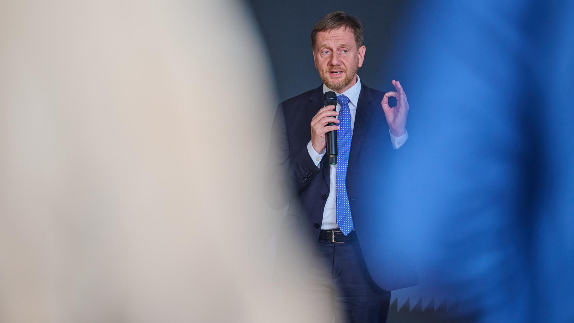 Michael Kretschmer (CDU), Ministerpräsident von Sachsen, spricht bei einem Richtfest in Dresden in ein Mikrofon und gestikuliert.