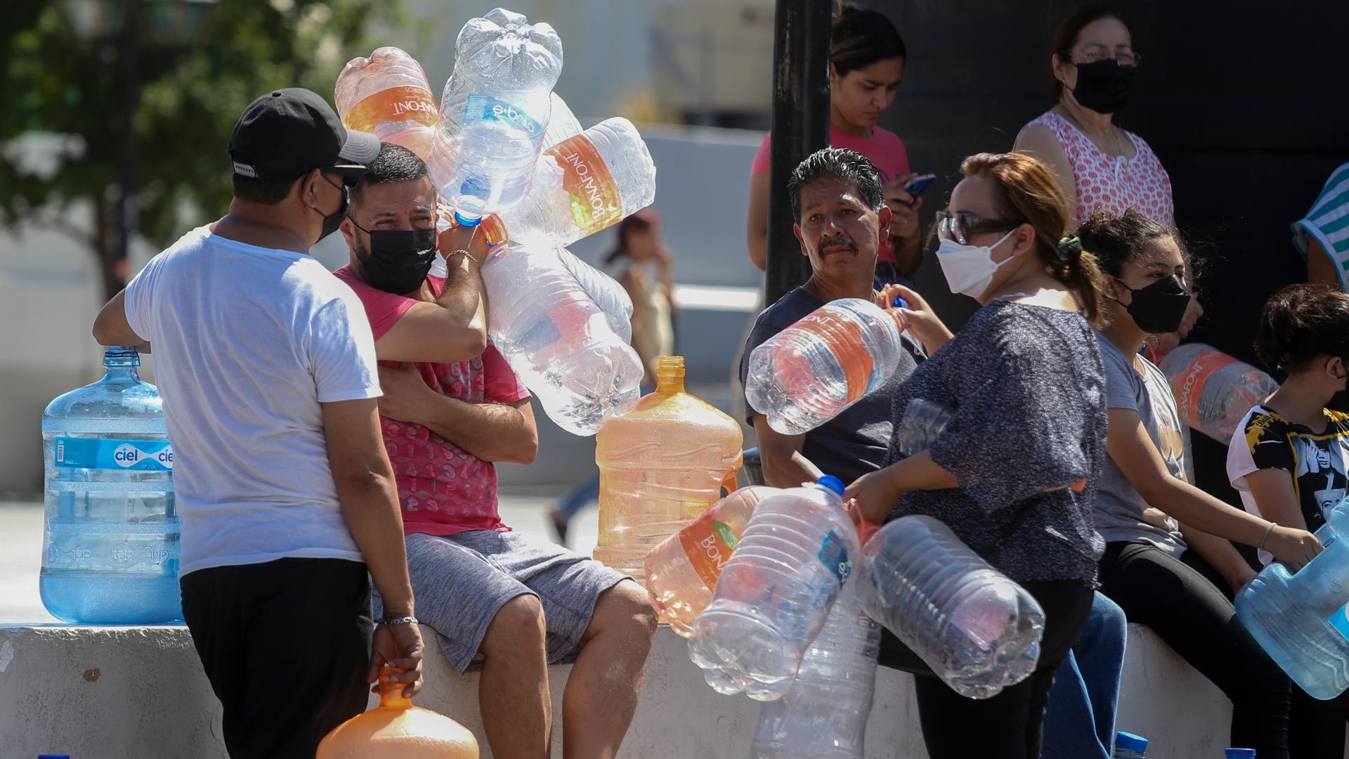 Menschen warten mit Plastikbehältern auf Wasserlieferungen an einer Sammelstelle in Mexiko.