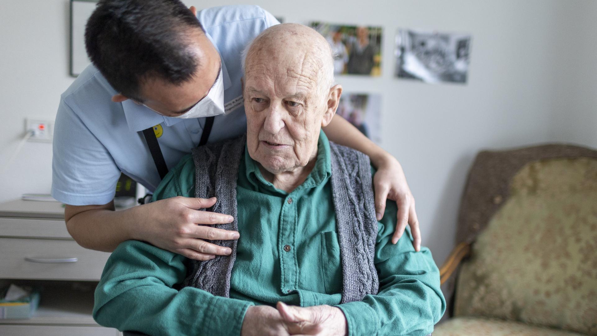 Ein Altenpfleger redet mit einem Bewohner im Pflegeheim.