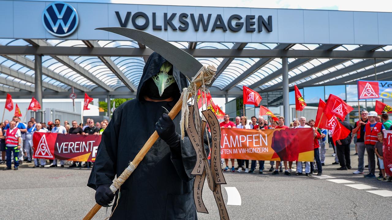 Ein Mann steht als Tod (Sensenmann) verkleidet während einer Informations- und Protestaktion der IG Metall vor dem VW-Werk in Zwickau. Ein Mann steht als Tod (Sensenmann) verkleidet während einer Informations- und Protestaktion der IG Metall vor dem VW-Werk in Zwickau.