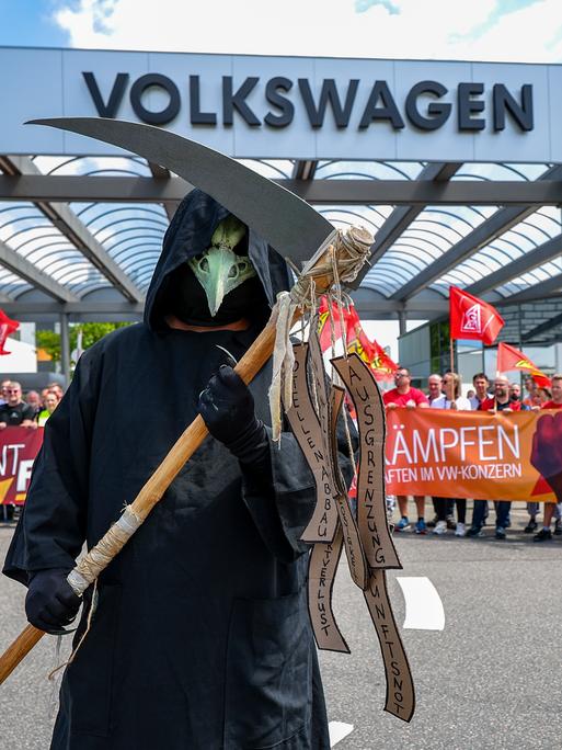 Ein Mann steht als Tod (Sensenmann) verkleidet während einer Informations- und Protestaktion der IG Metall vor dem VW-Werk in Zwickau. 