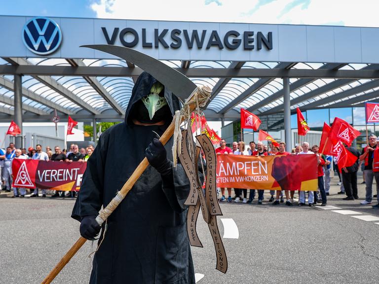 Ein Mann steht als Tod (Sensenmann) verkleidet während einer Informations- und Protestaktion der IG Metall vor dem VW-Werk in Zwickau. 