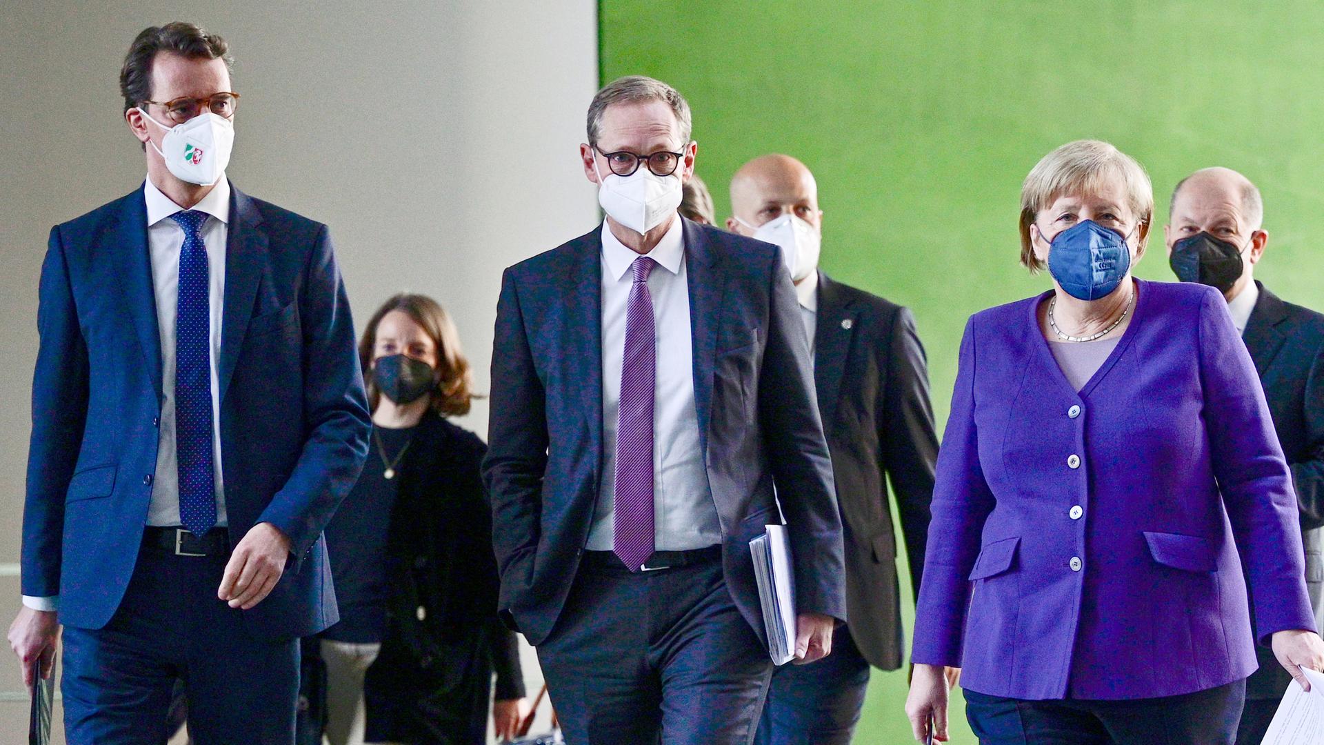 Die Politiker und Merkel laufen nebeneinander und hintereinander durch einen Gang, im Hintergrund eine graue und eine grüne Wand. Die Politiker und Merkel laufen nebeneinander und hintereinander durch einen Gang, im Hintergrund eine graue und eine grüne Wand.