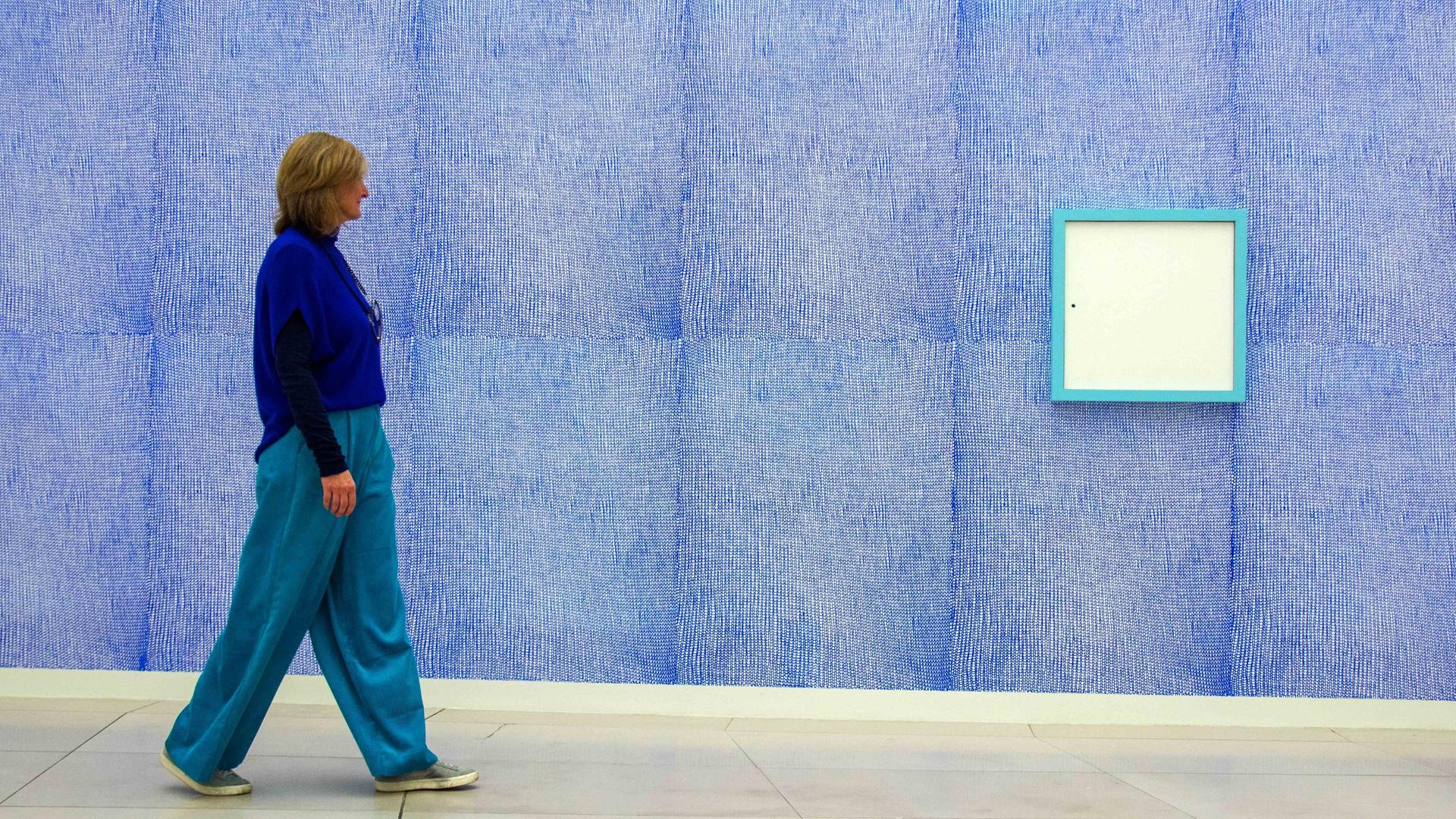 Eine Besucherin läuft an dem in blau gehaltenen Wandbild "Prisoner of Yourself" in der Ausstellung von Rosemarie Trockel im Museum für Moderne Kunst (MMK) in Frankfurt vorbei. 