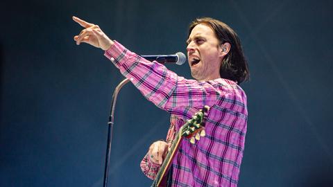 "Bilderbuch"-Frontmann Maurice Ernst beim Benefizkonzert We Stand With Ukraine im Wiener Ernst-Happel-Stadion. Er singt in ein Mikrofon und zeigt mit ausgestrecktem Arm in das Publikum.