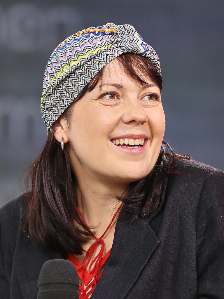 Dana von Suffrin sitzt mit einem Mikrofon auf einem Podium und lächelt ihr Gegenüber an. Sie trägt eine dekorative Kopfbedeckung.