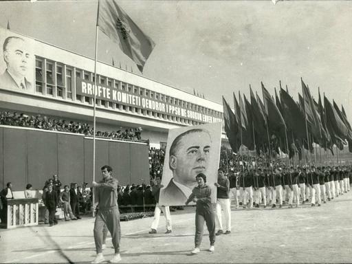 Historische Aufnahme aus Dezember 1977: Studenten marschieren mit Fahnen zur Feier des 20-jährigen Bestehens der Universität Tirana. Zwei Männer tragen zudem ein großes Plakat mit dem Konterfei von Enver Hoxha, dem damaligen kommunistischen Herrscher Albaniens.