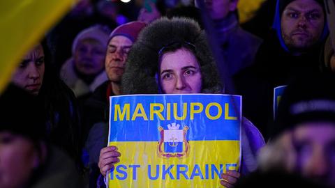 Anti-Kriegs-Demonstration in Berlin zum ersten Jahrestags des Angriffs Russlands auf die Ukraine. Eine Demonstrantin hält ein Pappschild mit der Aufschrift: "MARIUPOL IST UKRAINE".