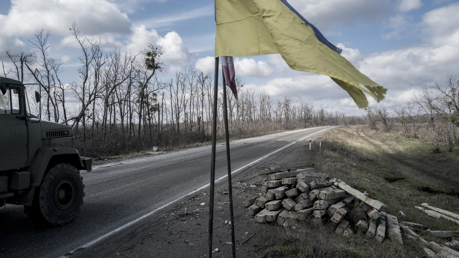 Ein Truck fährt auf einer Straße nach Slowiansk an einer ukrainischen Flagge vorbei.