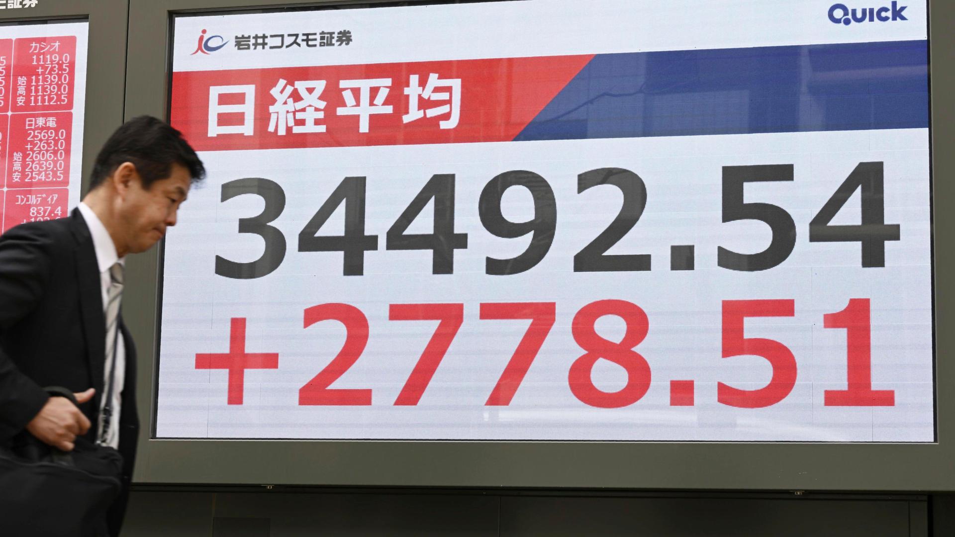 Ein Mann geht in einer Wertpapierfirma in Tokio an einer elektronischen Tafel vorbei, die den japanischen Nikkei 225-Index anzeigt. 