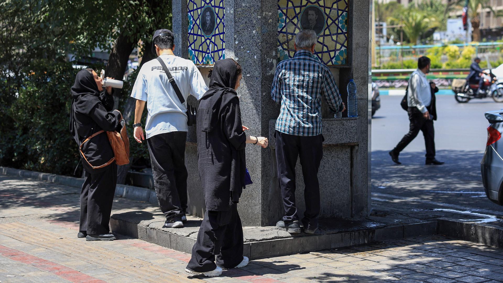 Menschen stehen an einem Trinkwasserbrunnen im Iran. Menschen stehen an einem Trinkwasserbrunnen im Iran.