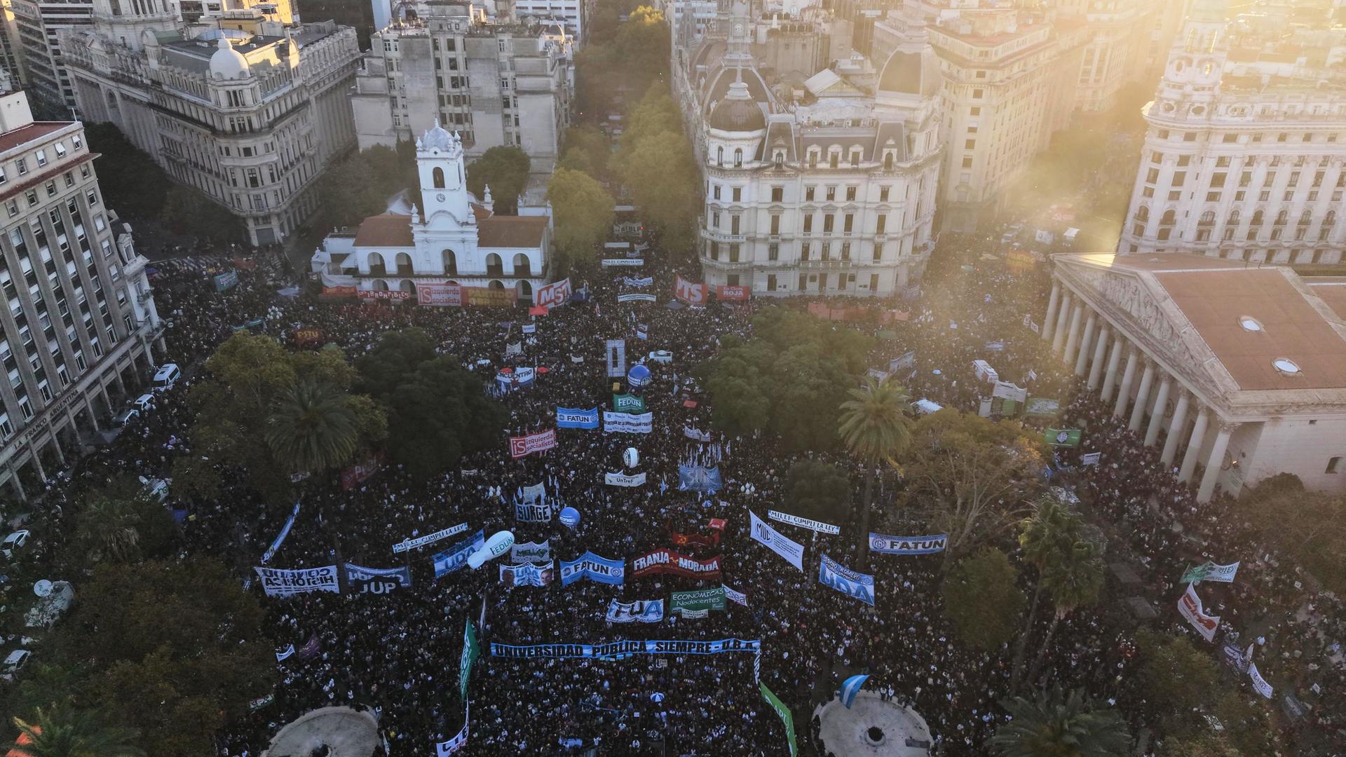 Menschen protestieren in Buenos Aires, Argentinien, sie halten Plakate. Das Foto ist aus der Vogelperspektive aufgenommen.