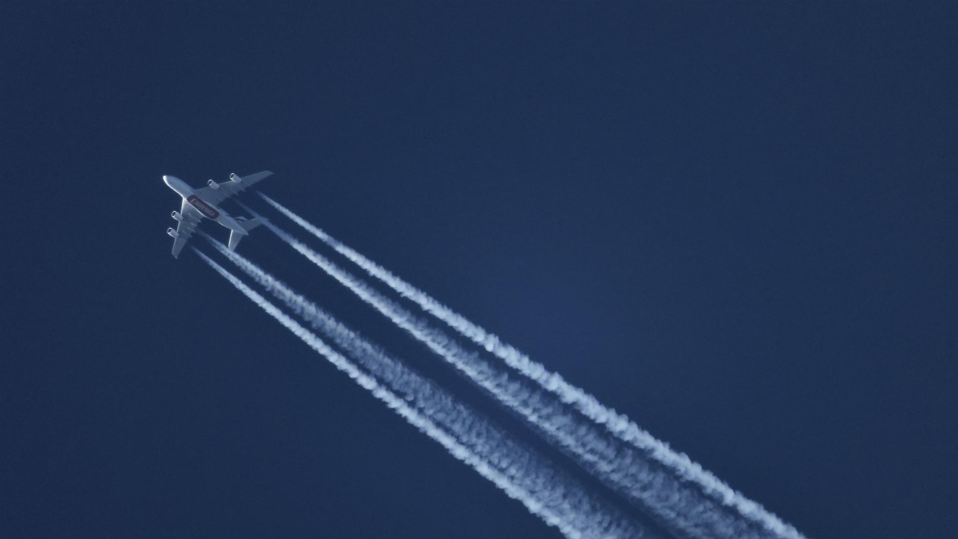 Flugzeug hinterlässt Kondensstreifen am Himmel.