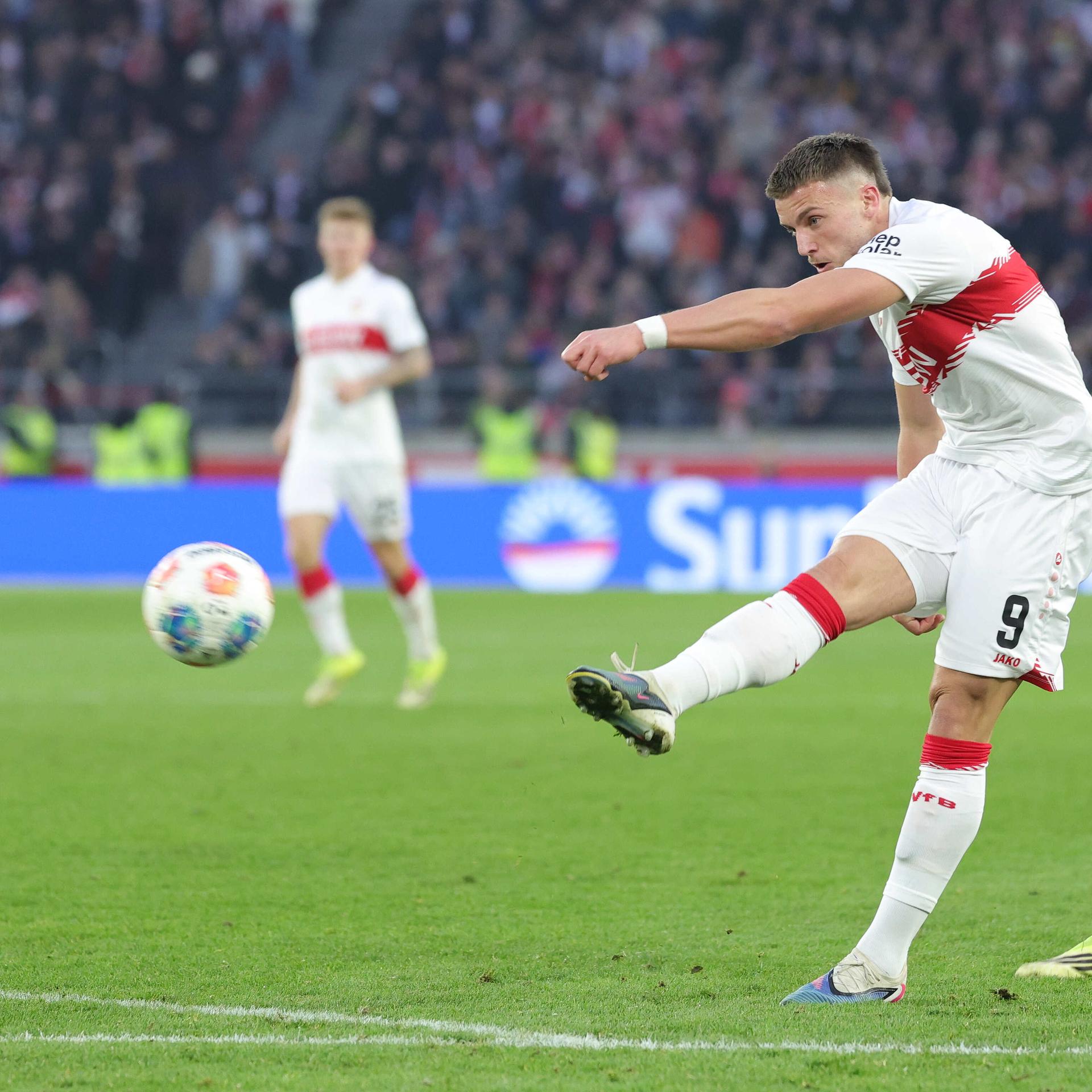 Ein Fußballer im weißen Trikot schießt auf den Ball.