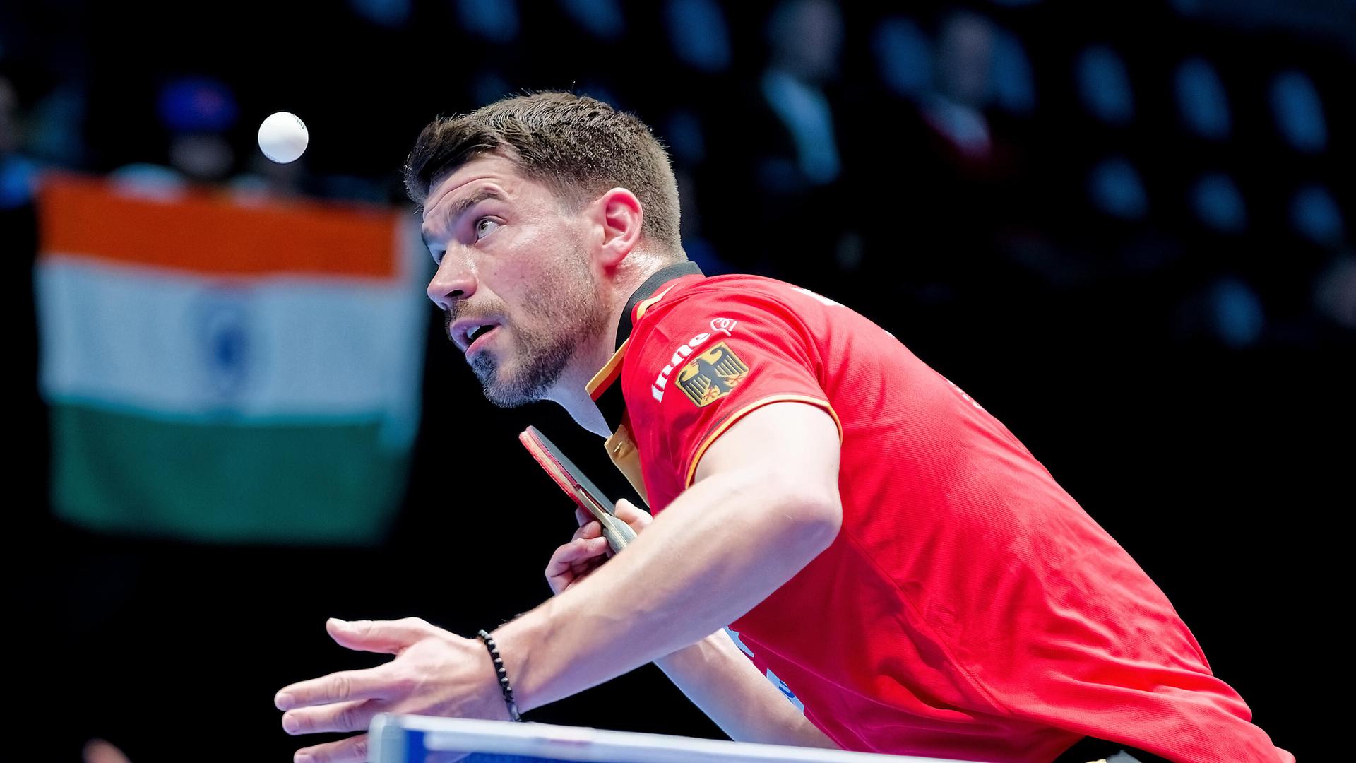 Das Bild zeigt Patrick Franziska bei den Team-Weltmeisterschaften im Tischtennis in London. Er trägt ein rotes Trikot, holt mit dem Tischtennisschläger aus und blickt konzentriert auf den fliegenden Ball.