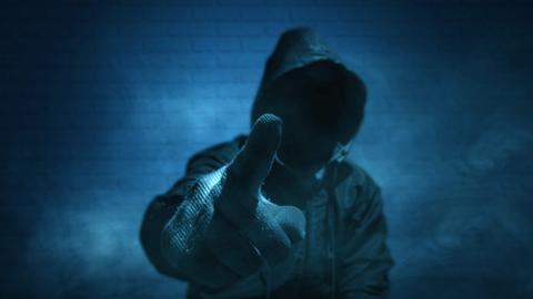 Ein unkenntlicher Mann mit Hoodie und erhobenem Zeigefinger in Handschuhen.