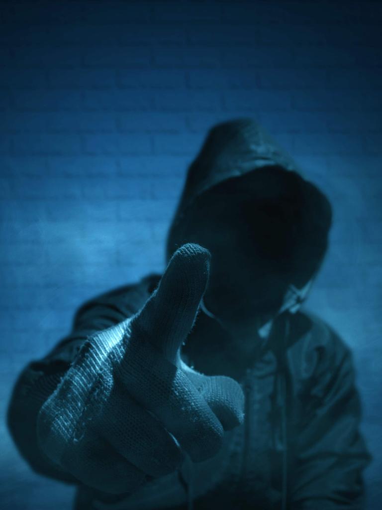Ein unkenntlicher Mann mit Hoodie und erhobenem Zeigefinger in Handschuhen.