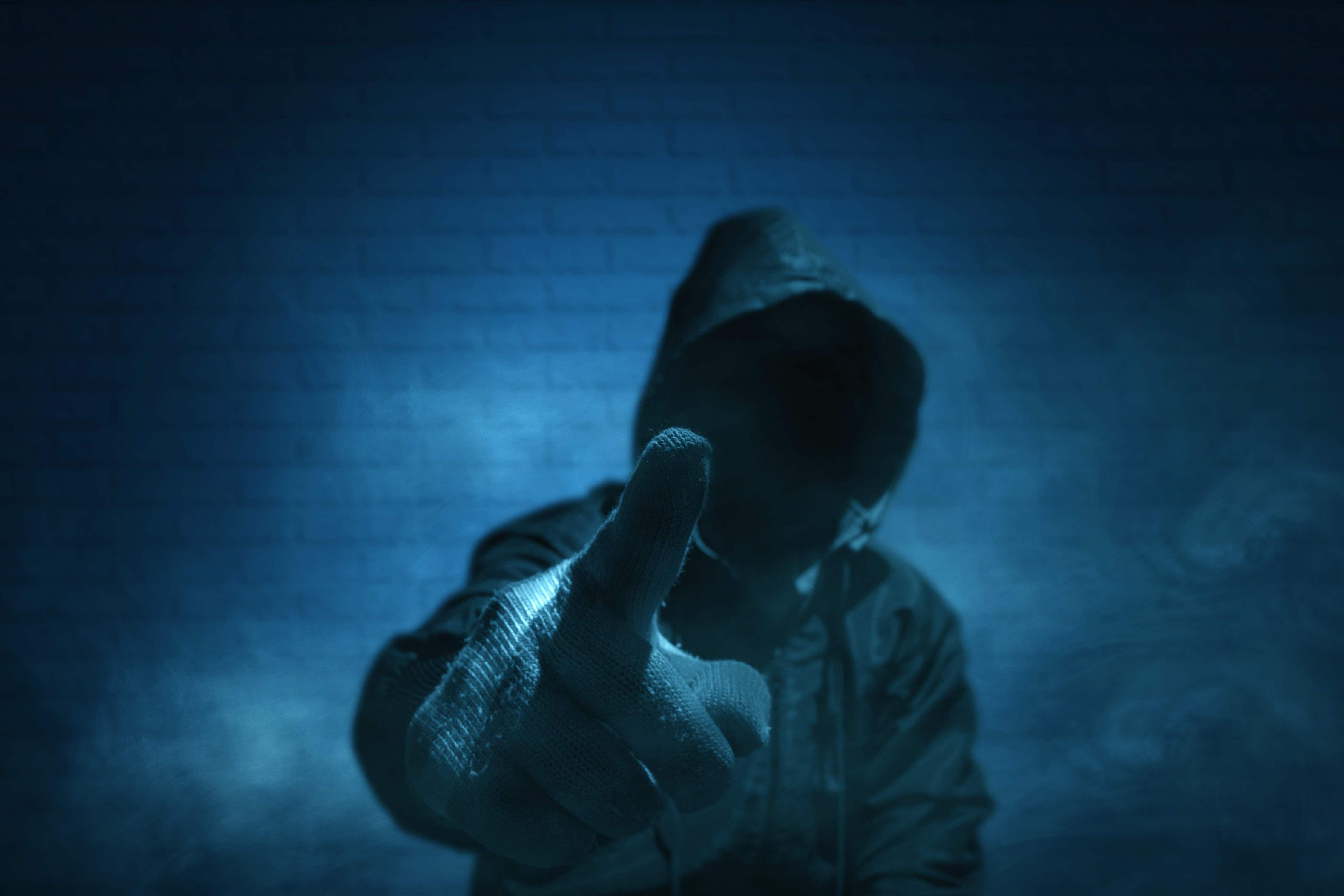 Ein unkenntlicher Mann mit Hoodie und erhobenem Zeigefinger in Handschuhen.