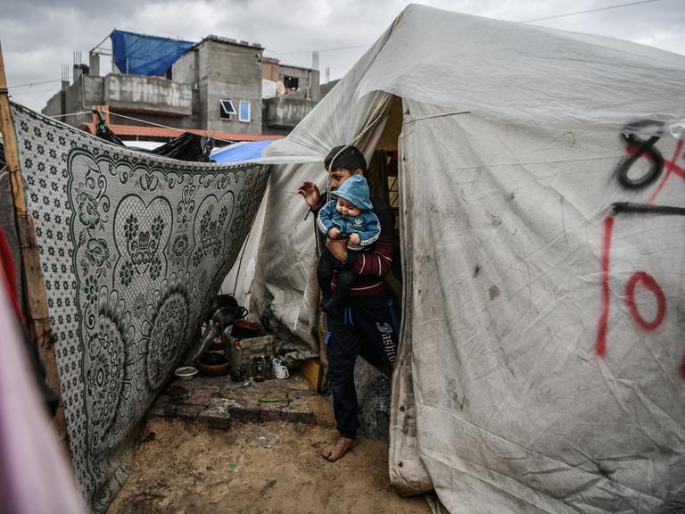 Ein 14-jährige Palästinenser, der seine Mutter verloren hat und wegen der israelischen Angriffe auf den Gazastreifen nichts von seinem Vater gehört hat, umarmt seinen 6 Monate alten kleinen Bruder vor dem behelfsmäßigen Zelt, in dem sie am 28. Januar 2024 in Rafah, Gaza, Schutz suchen.