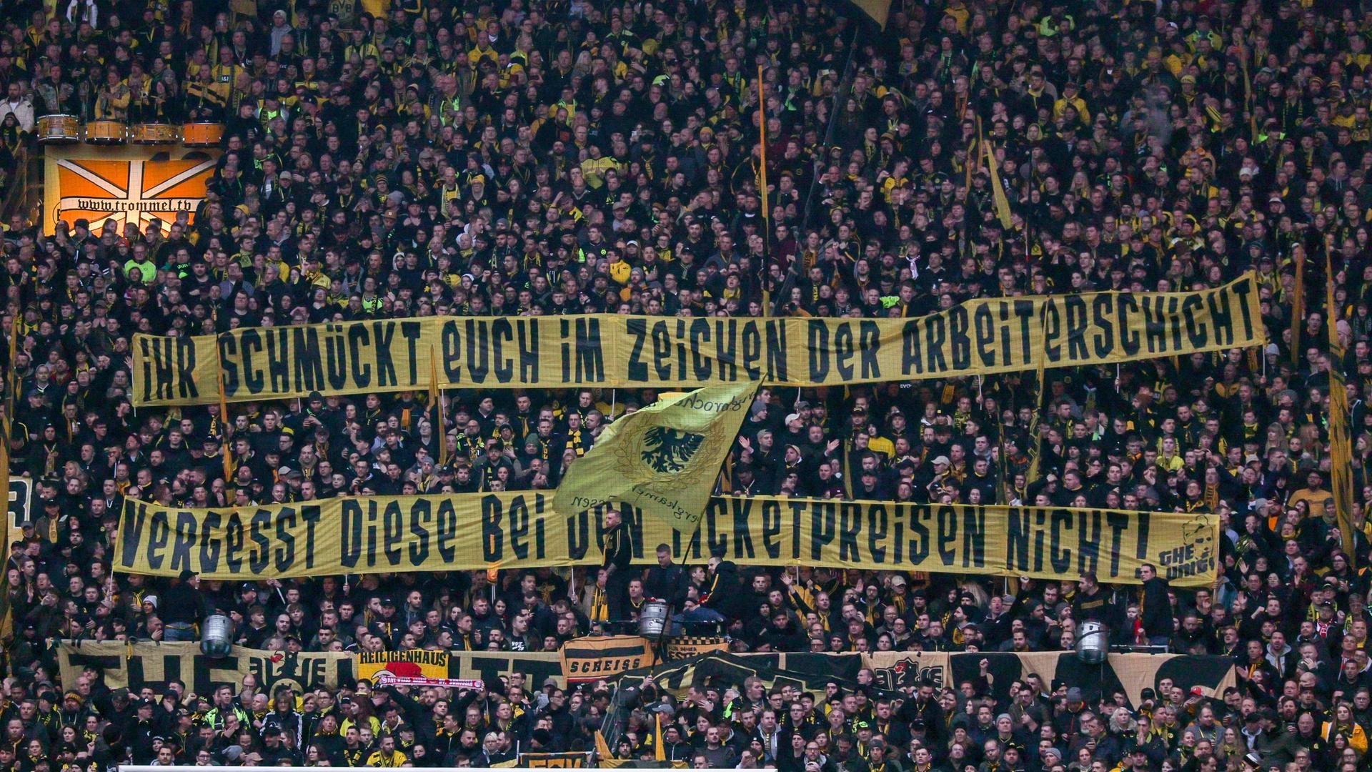 Fans von Fußball-Bundesligist Borussia Dortmund äußern mit Bannern Kritik am Sondertrikot: "Ihr schmückt euch im Zeichen der Arbeiterschaft, vergesst diese bei den Ticketpreisen nicht!"