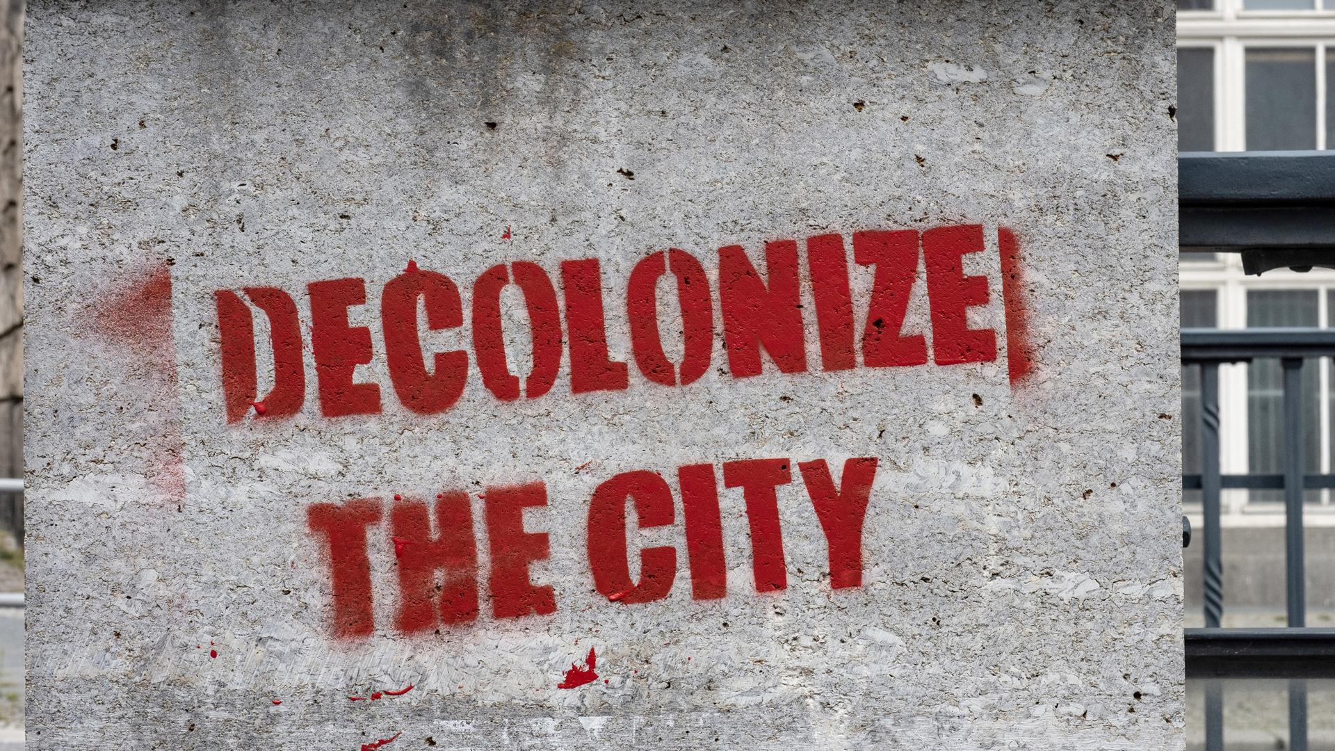 Ein Graffiti mit dem Schriftzug "decolonize the city" wurde an eine Botenpfeiler gesprüht.