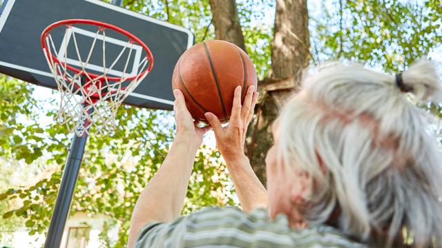 Konzentrierter sportlicher Senior mit Basket-Ball beim Frei-Wurf-Training für Genauigkeit