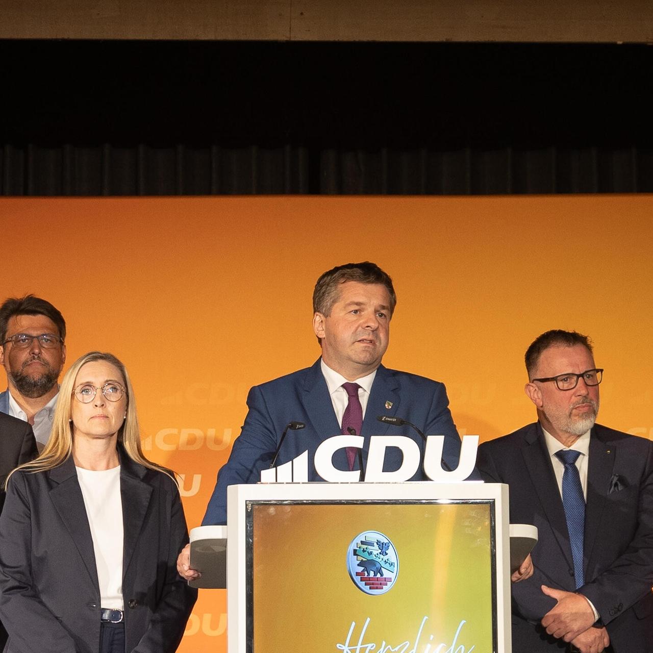 Sven Schulze steht an einem Rednerpult mit dem Logo der CDU und spricht. Neben ihm stehen mehrere CDU-Landespolitiker.
