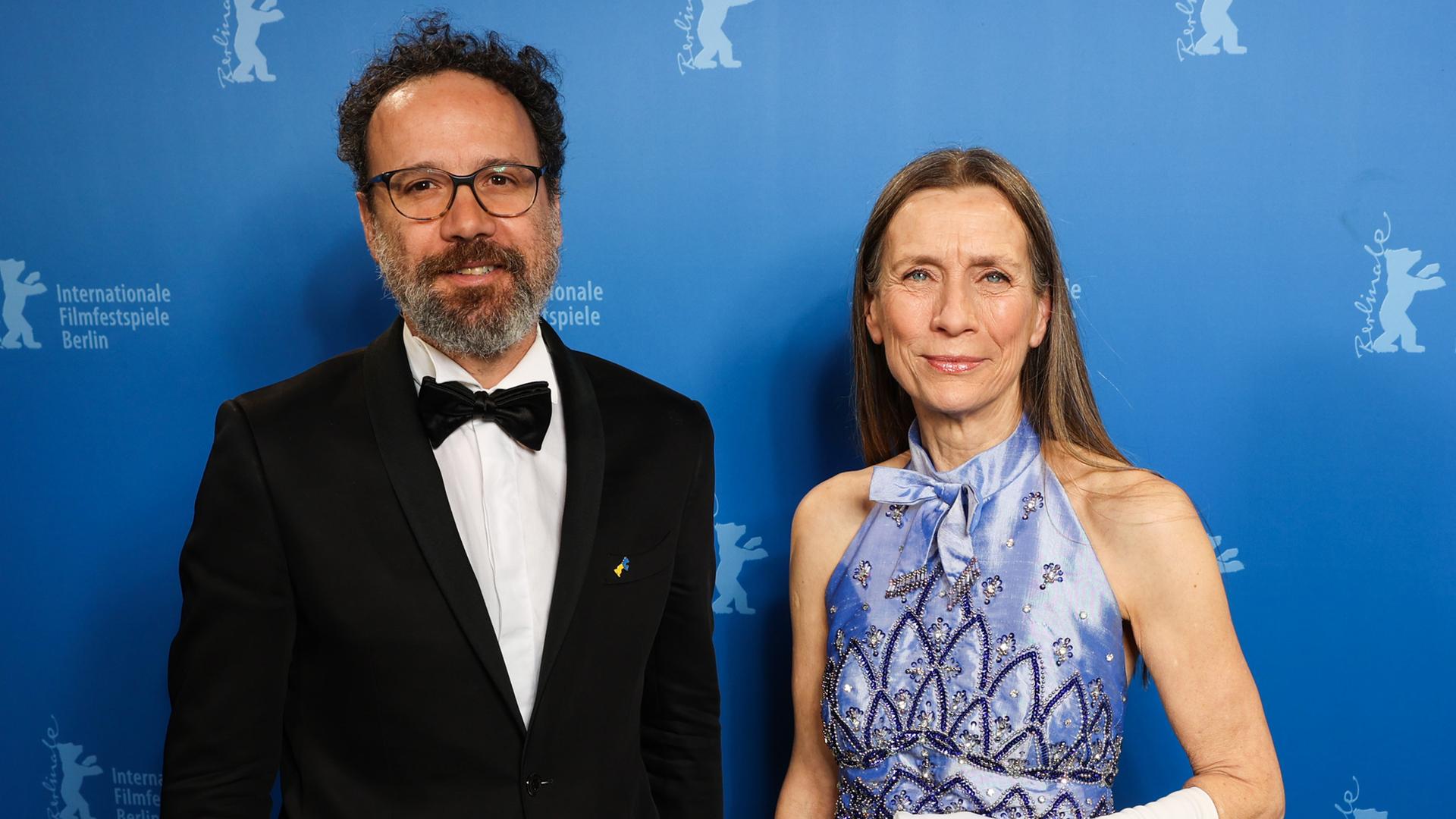Carlo Chatrian und Mariette Rissenbeek vor einer Wand mit Symbolen der Internationalen Filmfestspiele Berlin