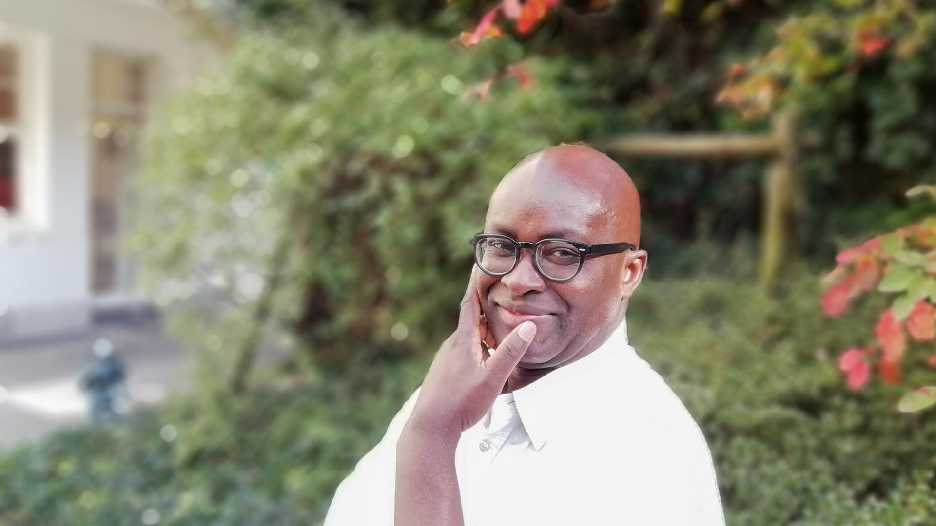 Joseph-Achille Mbembe, Philosoph und Politikwissenschaftler aus Kamerun, trägt ein weißes Hemd und Brille und befindet sich in einem Garten. Joseph-Achille Mbembe, Philosoph und Politikwissenschaftler aus Kamerun, trägt ein weißes Hemd und Brille und befindet sich in einem Garten.