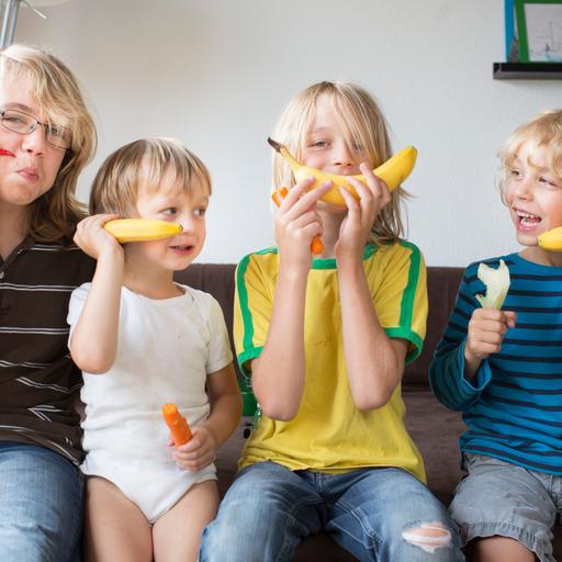 Brüder im Alter von 3, 6, 8 und 12 Jahren spielen im Wohnzimmer Bananentelefon.