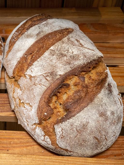 Zwei Brotlaibe liegen nebeneinander in einem Holzregal.