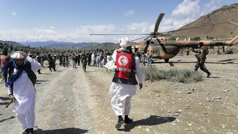 Afghanistan: Ein Helfer des Roten Halbmond geht zu einem Hubschrauber. Dahinter stehen viele Menschen. Afghanistan: Ein Helfer des Roten Halbmond geht zu einem Hubschrauber. Dahinter stehen viele Menschen.
