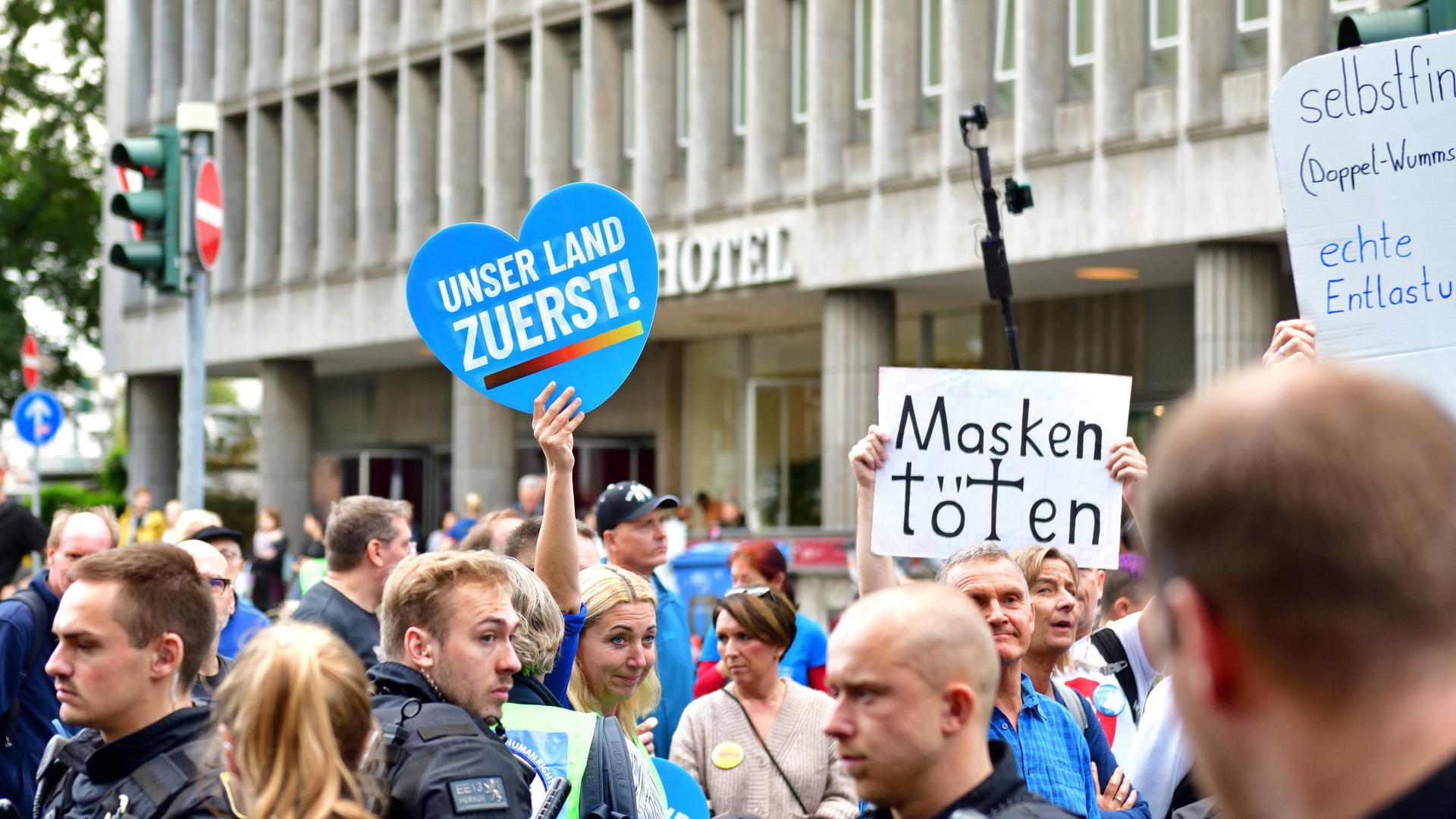 Foto einer Querdenker-Demo in Frankfurt am Main am 22.10.2022, bei der Schilder mit der Aufschrift "Deutschland zuerst!" und "Masken töten" hochgehalten werden.