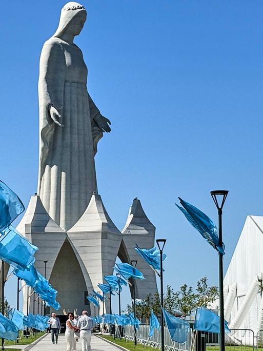 Auf dem Weg zu der riesigen Statue stehen unzählige blaue Fahnen. Darüber ein stahlblauer wolkenloser Himmel. Auf dem Weg zu der riesigen Statue stehen unzählige blaue Fahnen. Darüber ein stahlblauer wolkenloser Himmel.