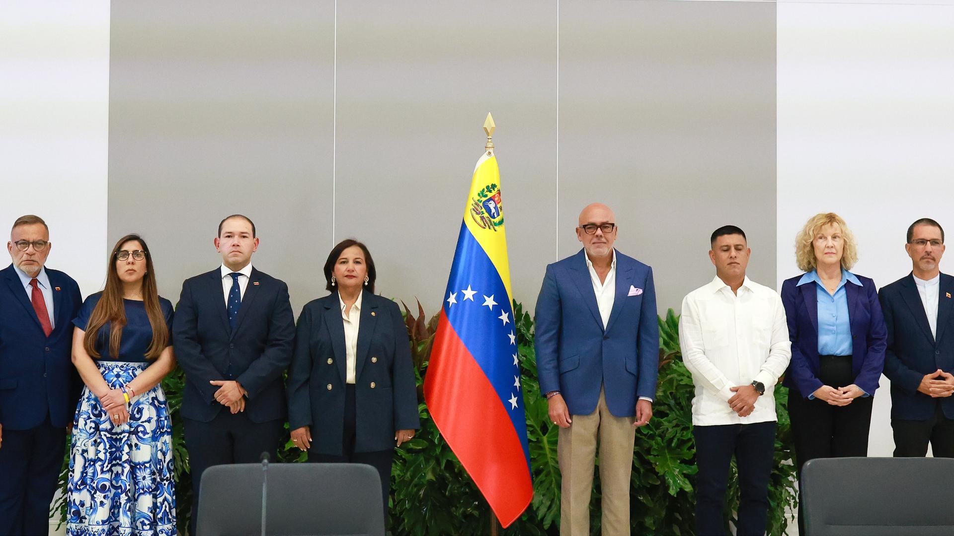 Zahlreiche Politikerinnen und Politiker stehen links und rechts neben der venezolanischen Flagge aufgereiht und getrennt in zwei unterschiedliche politische Lager. Zahlreiche Politikerinnen und Politiker stehen links und rechts neben der venezolanischen Flagge aufgereiht und getrennt in zwei unterschiedliche politische Lager.