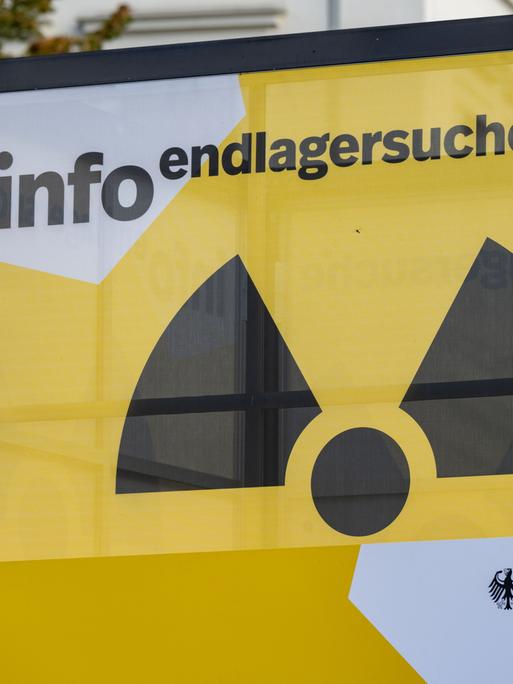 Zu sehen ist ein Infostandstand in Würfelform. Auf den Seiten ist das Zeichen für Radioaktivität abgebildet. Darüber steht geschrieben: „Info Endlagersuche“. 